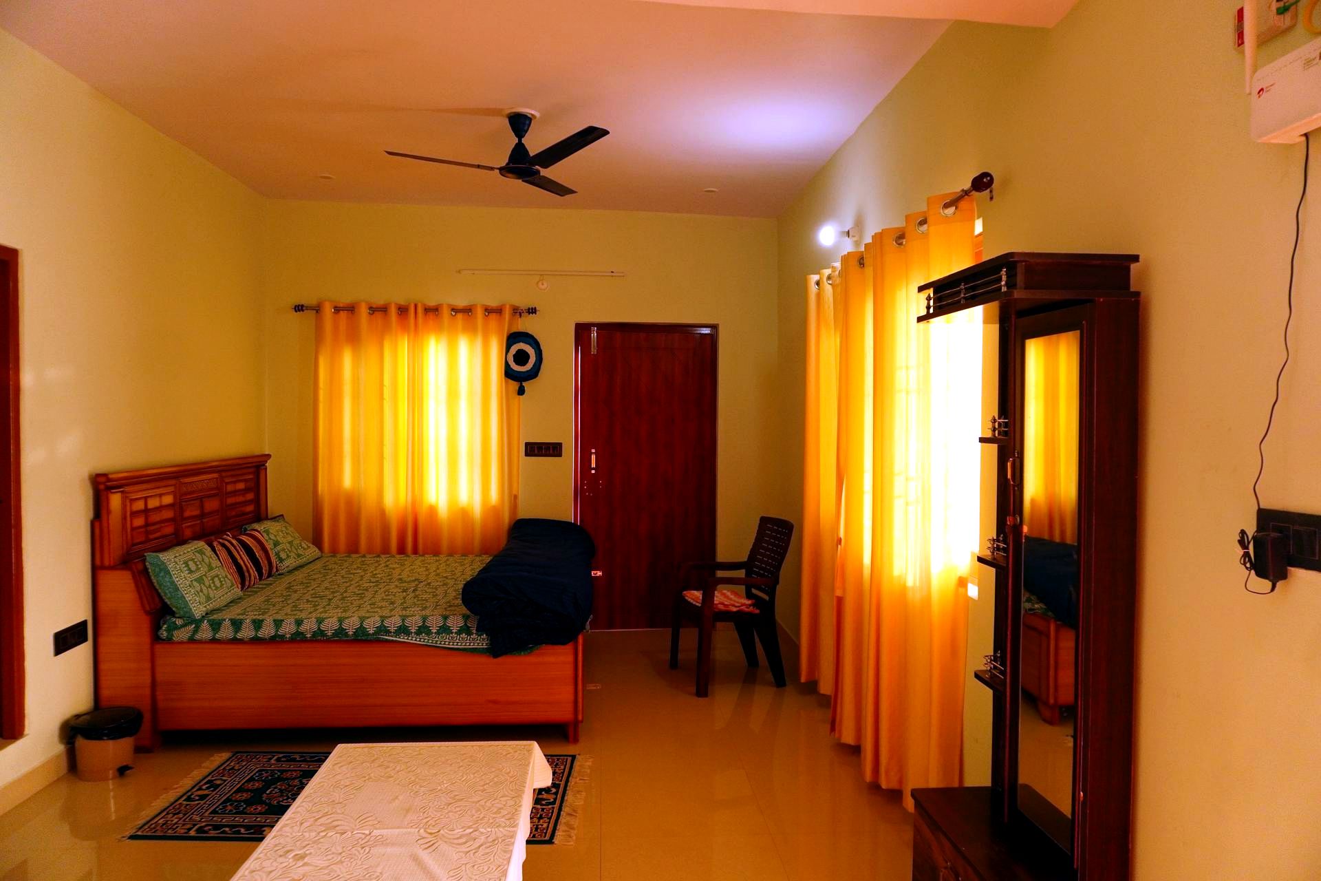 Bedroom with green bedcover, wardrobe mirror, and warm lighting